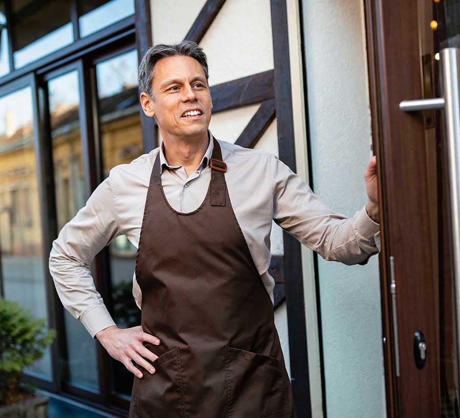 A business owner stands at the door smiling