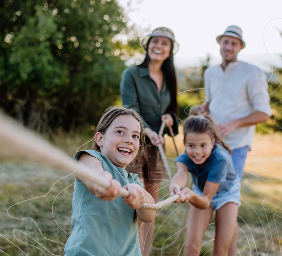 A family pulls on a rope together as they smile