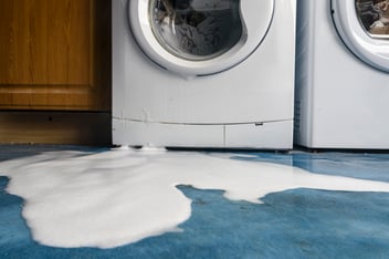 broken washing machine leaking on the floor